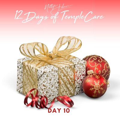 White and gold patterned gift box with gold ribbon and red ornaments.