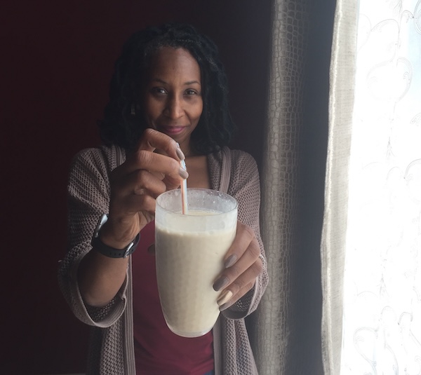 Nettye Johnson offering a smoothie in front of a window